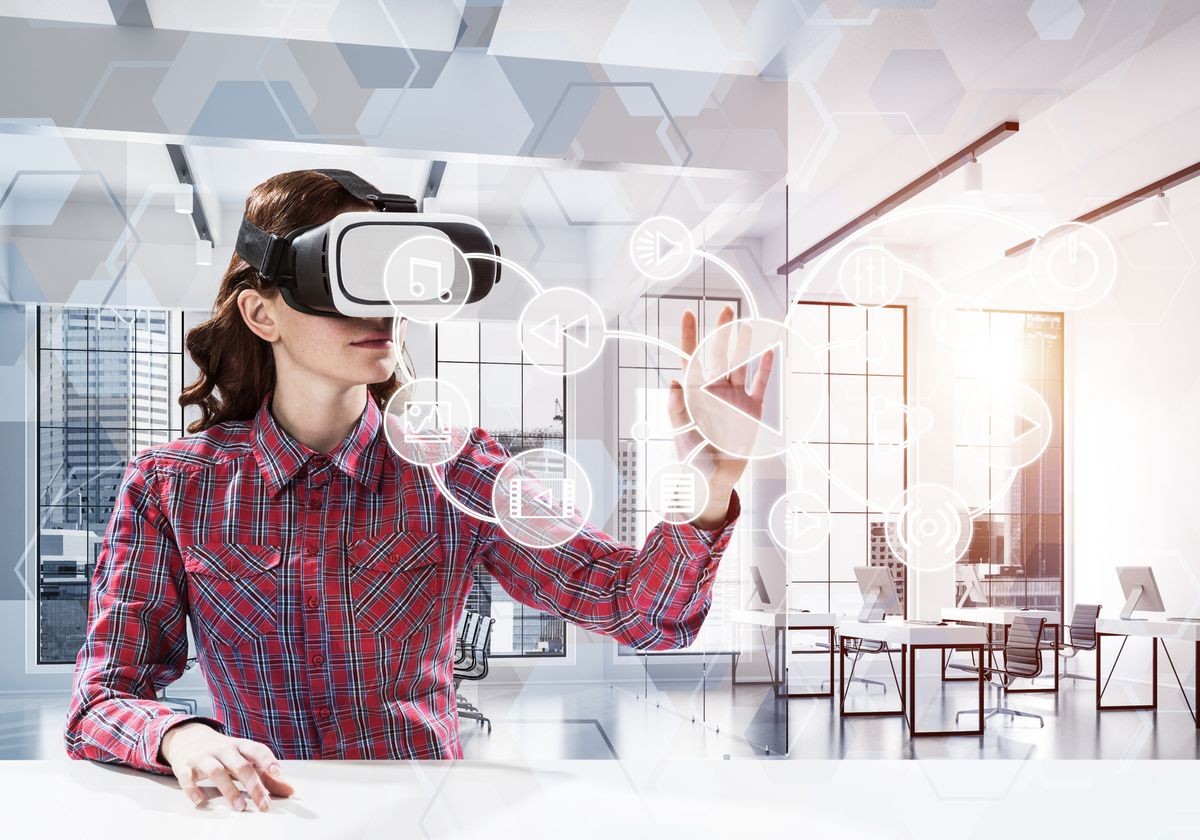 Conceptual image of young woman in checkered shirt using virtual reality headset with media interface while sitting inside bright building. Up to date technologies for education